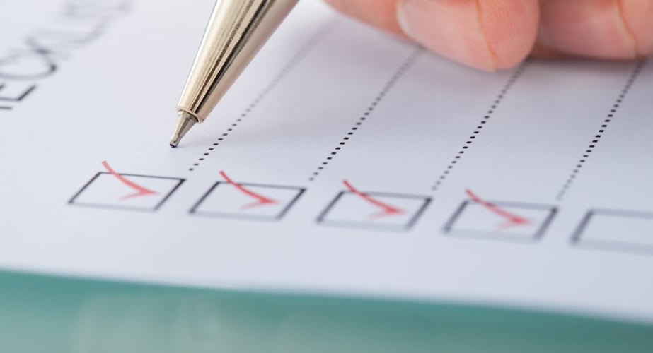 image of a hand holding a pen and checking off items on a checklist