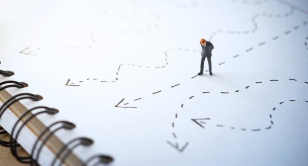  A piece of paper with multiple different routes drawn on, and a man deciding which route to follow