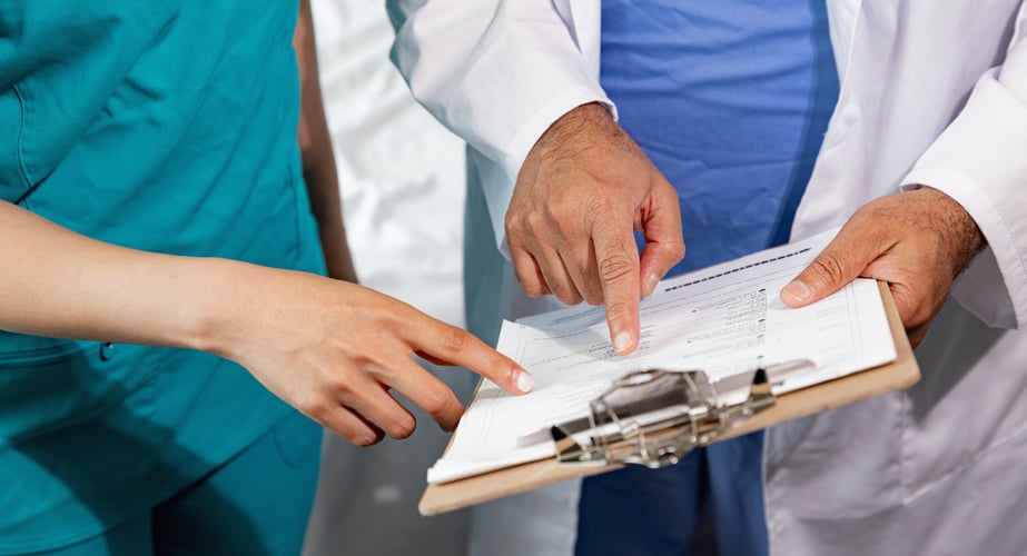 Image of a doctor indicating something to a nurse on a patient medical record