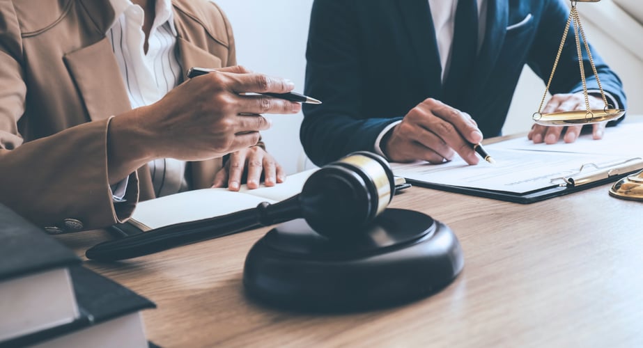 Image of a gavel and two people reviewing documents at a desk